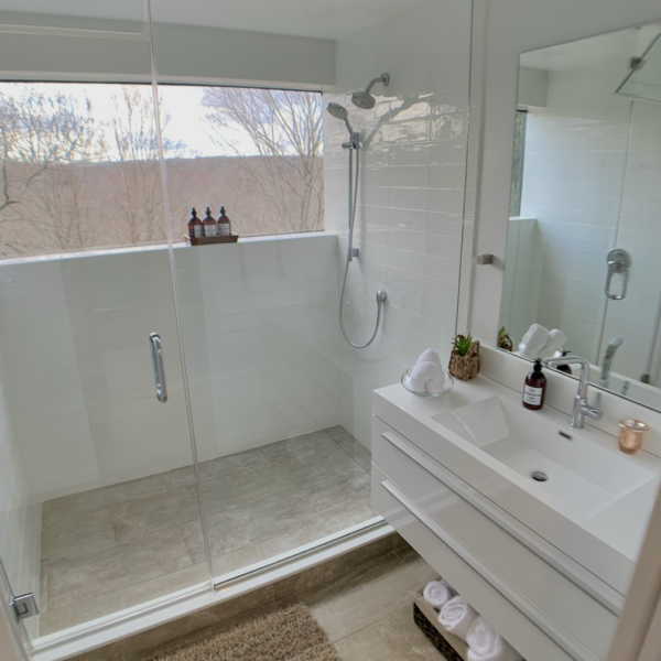 A shower area with a glass barrier next to the vanity